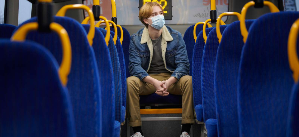 Photo: Ricky Molloy / Norden.org En dreng sidder alene i en bus med mundbind på.