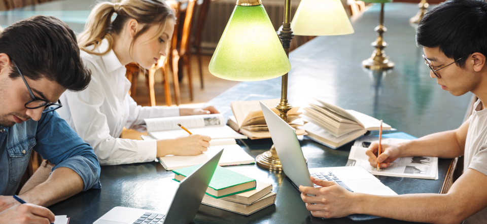 Three people studying in a library