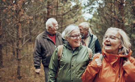 Four older people walking in the forest.