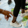 Young migrants standing on a world map
