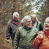 Four older people walking in the forest.