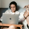 Woman with computer sitting in a sofa, petting a dog